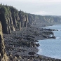 Photographie couleur d’une falaise en roche grise le long d’un rivage