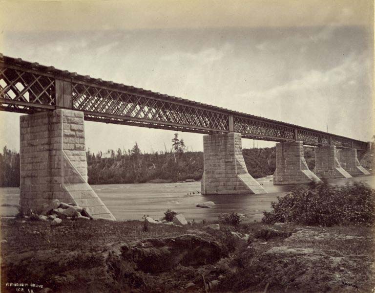 Photographie noir et blanc d'un pont ferroviaire avec piliers de granite enjambant une rivière