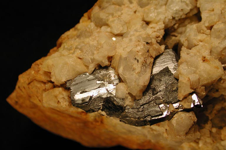 Image couleur de roche métallique grise apparaissant à travers les fissures d’une roche orange