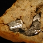 Image couleur de roche métallique grise apparaissant à travers les fissures d’une roche orange