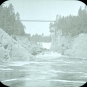 Image noir et blanc de la rivière, des rives rocheuses et, en arrière-plan, d’un pont suspendu