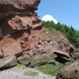 Colour photograph of a red rock cliff with large blocks of rock near the bottom