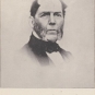 Photographie noir et blanc d’un homme atteint d’une calvitie naissante et qui porte des favoris