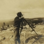 Photographie noir et blanc d’un homme sur des rochers avec de l’équipement d’arpentage
