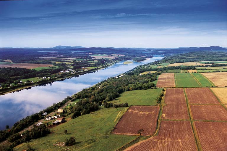 Colour photograph of a river with green fields on both sides
