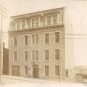 Black and white photograph of a old four-storey building with windows facing the street